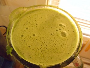 blender jug filled with green smoothie